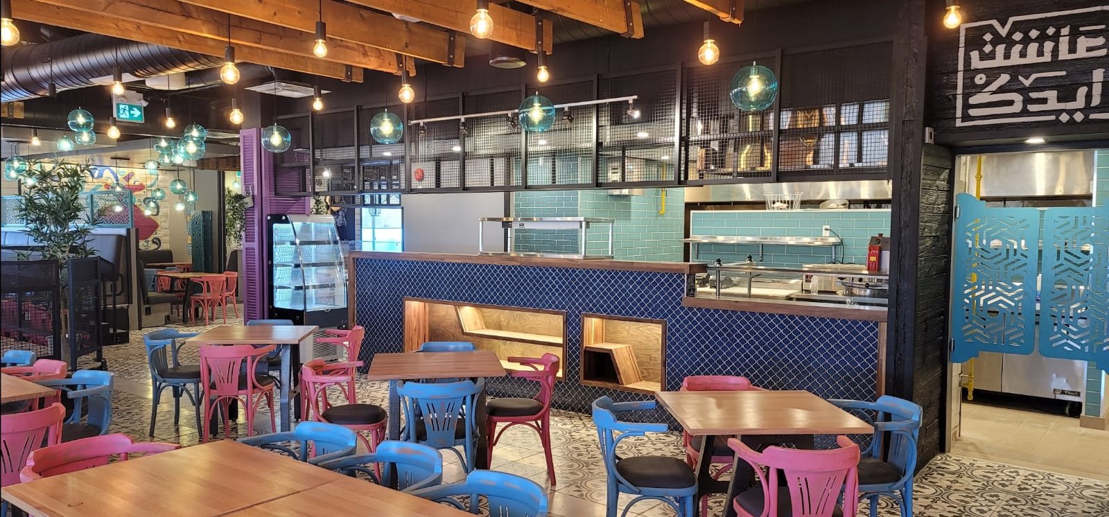 Inside Moods: teal glass lamps, pink and blue chairs and the open kitchen